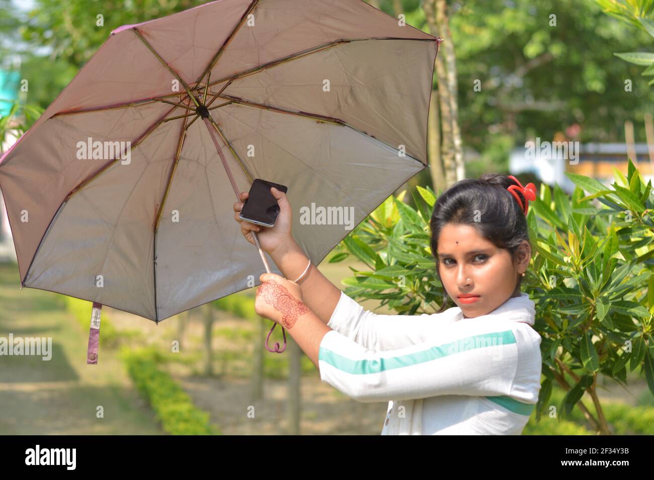 Indian Bengali teenage girl cotton white wearing salwar kameez and dhupatta opening an umbrella, selective focusing Stock Photo