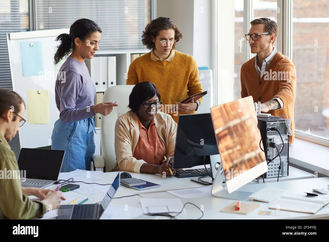 Portrait of diverse IT development team using computer together while working in software production studio Stock Photo