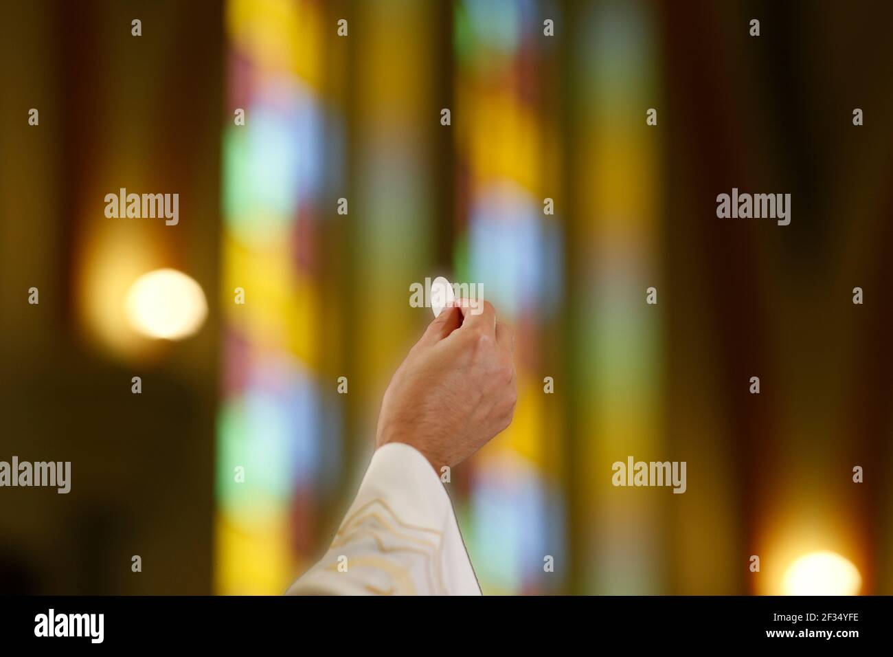 Detail with the priest's hand holding a host at Catholic Mass - Sacred Host Stock Photo