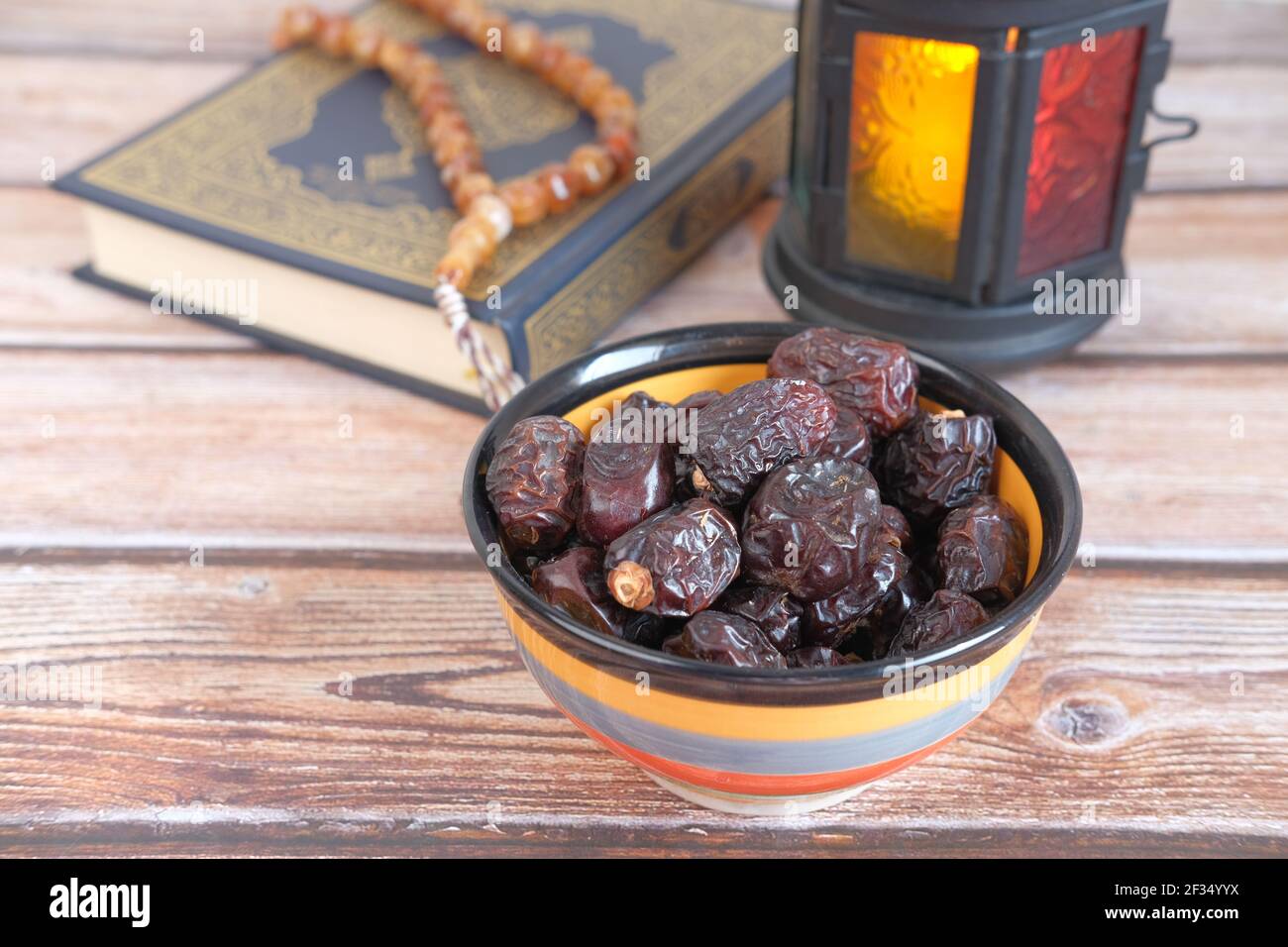 close up of fresh date fruit in a bowl and quran on background  Stock Photo
