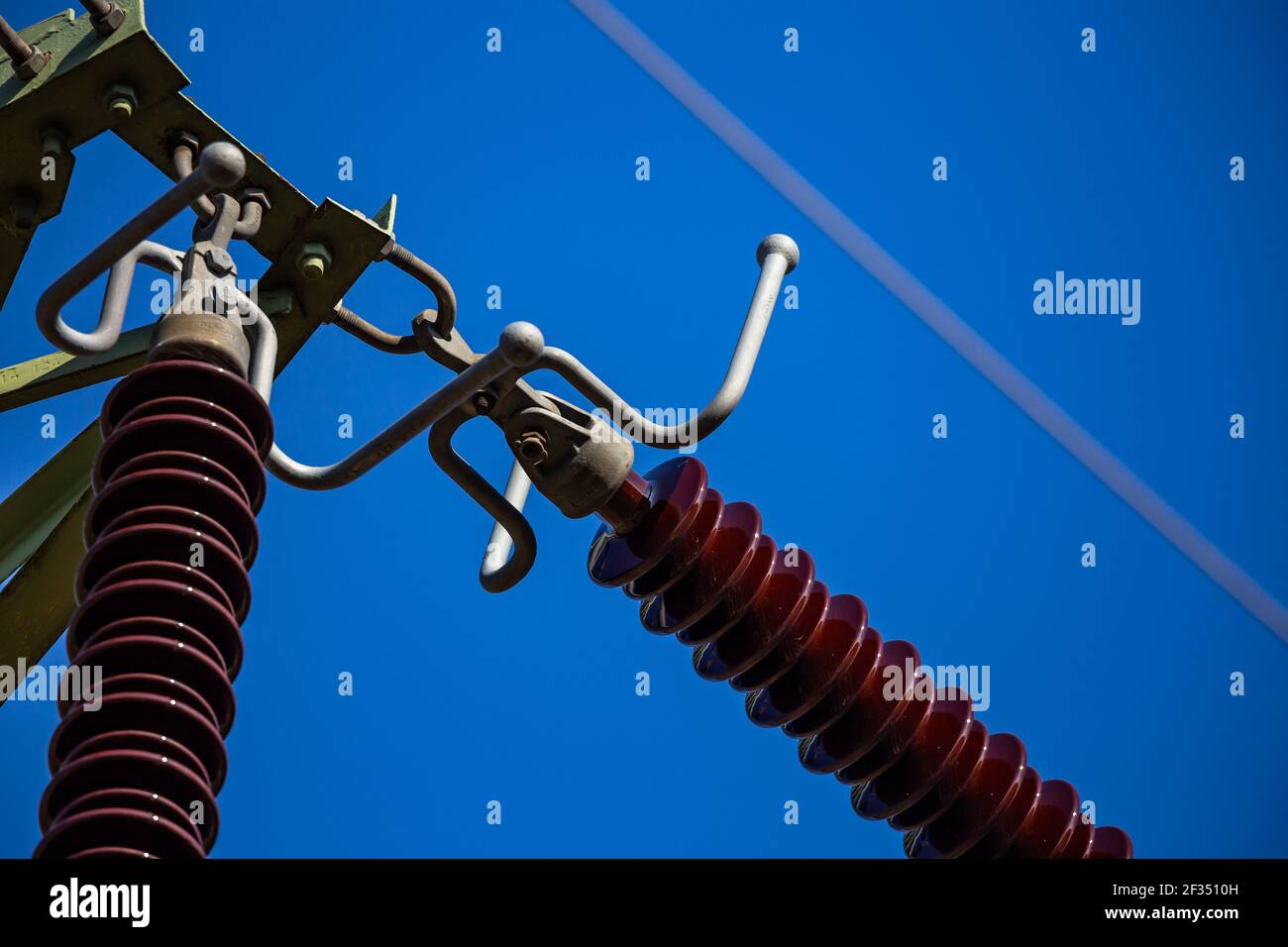 Close-up of insulators on high voltage pylons against the background of blue sky. Made in a sunny day, deep blue skies Stock Photo