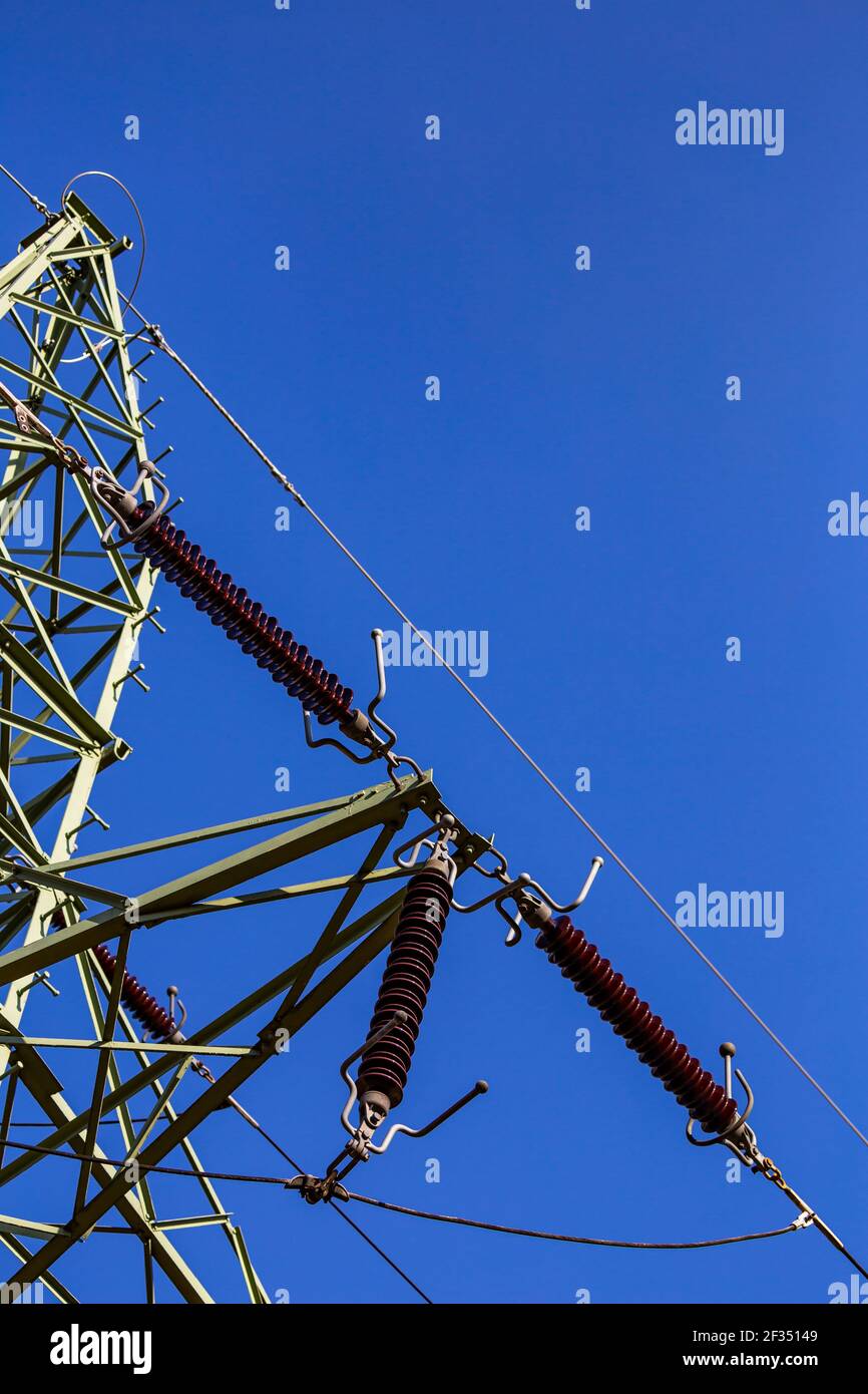 Close-up of insulators on high voltage pylons against the background of blue sky. Made in a sunny day, deep blue skies Stock Photo