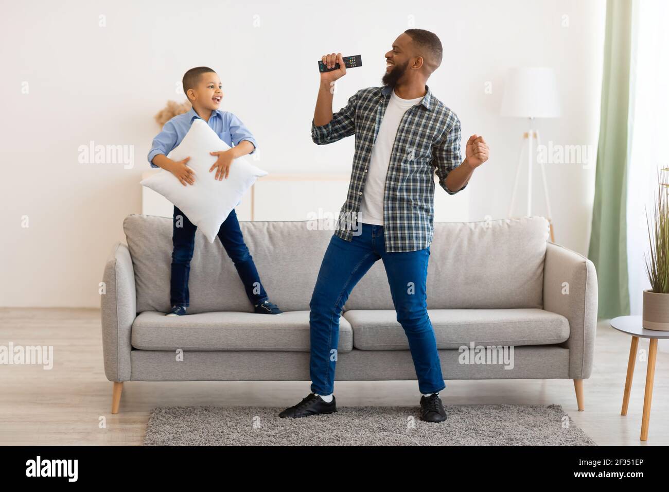 Happy Black Father And Son Having Fun Singing At Home Stock Photo