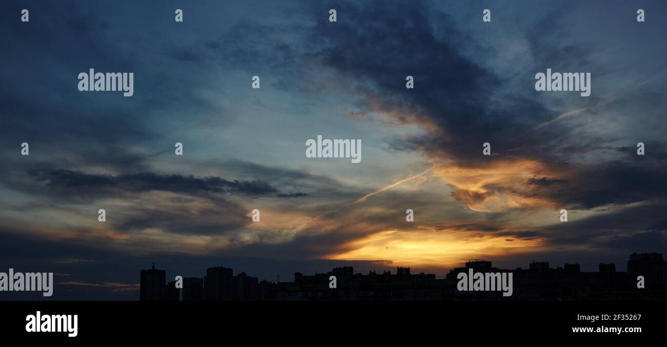 Colorful dramatic sky with clouds at sunset. City during warm sunset ...