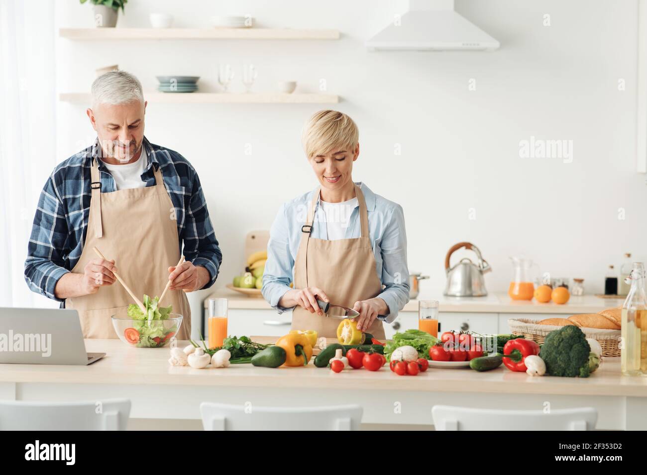 Couple preparing healthy vegetarian salad, enjoying process on modern cozy kitchen, cooking together Stock Photo