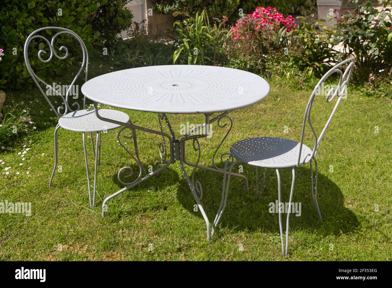 Gray table and chairs in wrought iron in a garden Stock Photo Alamy