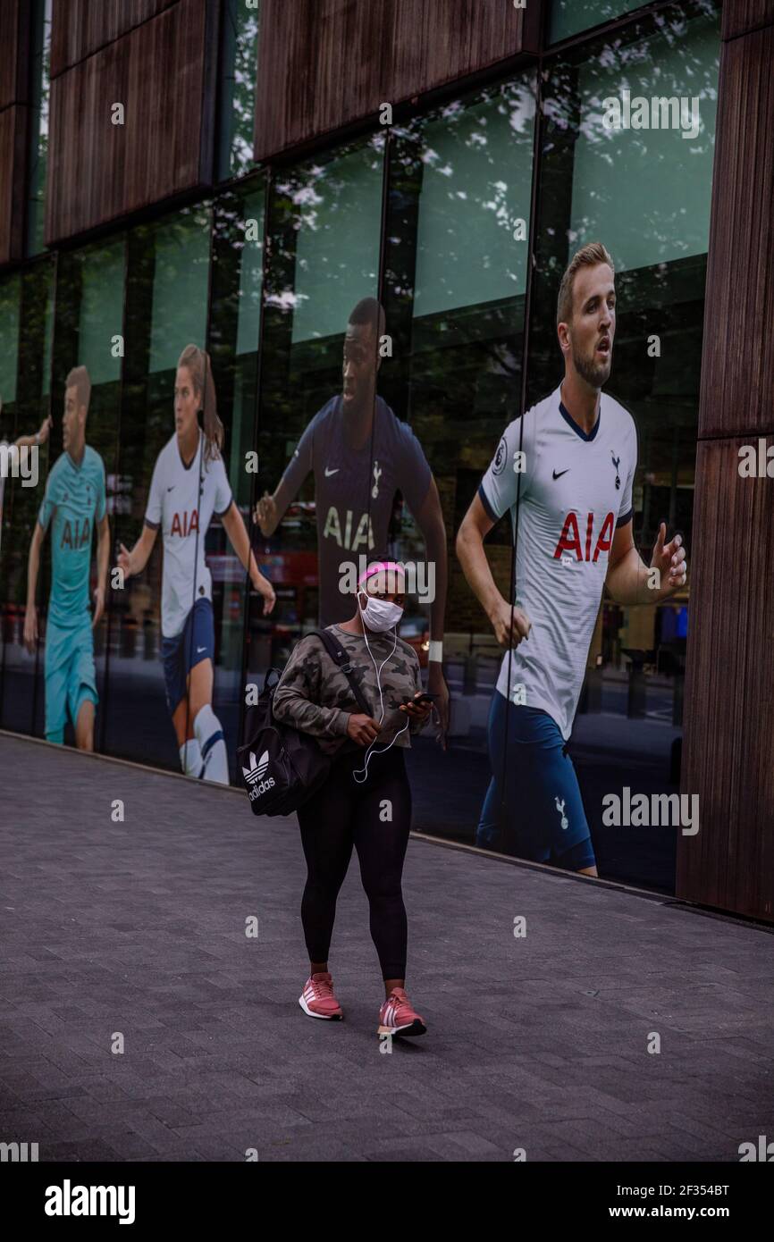 A member if the public wearing a face mask walking pass the Tottenham Hotspur club shop before the Premier League match back following the Coronavirus Stock Photo