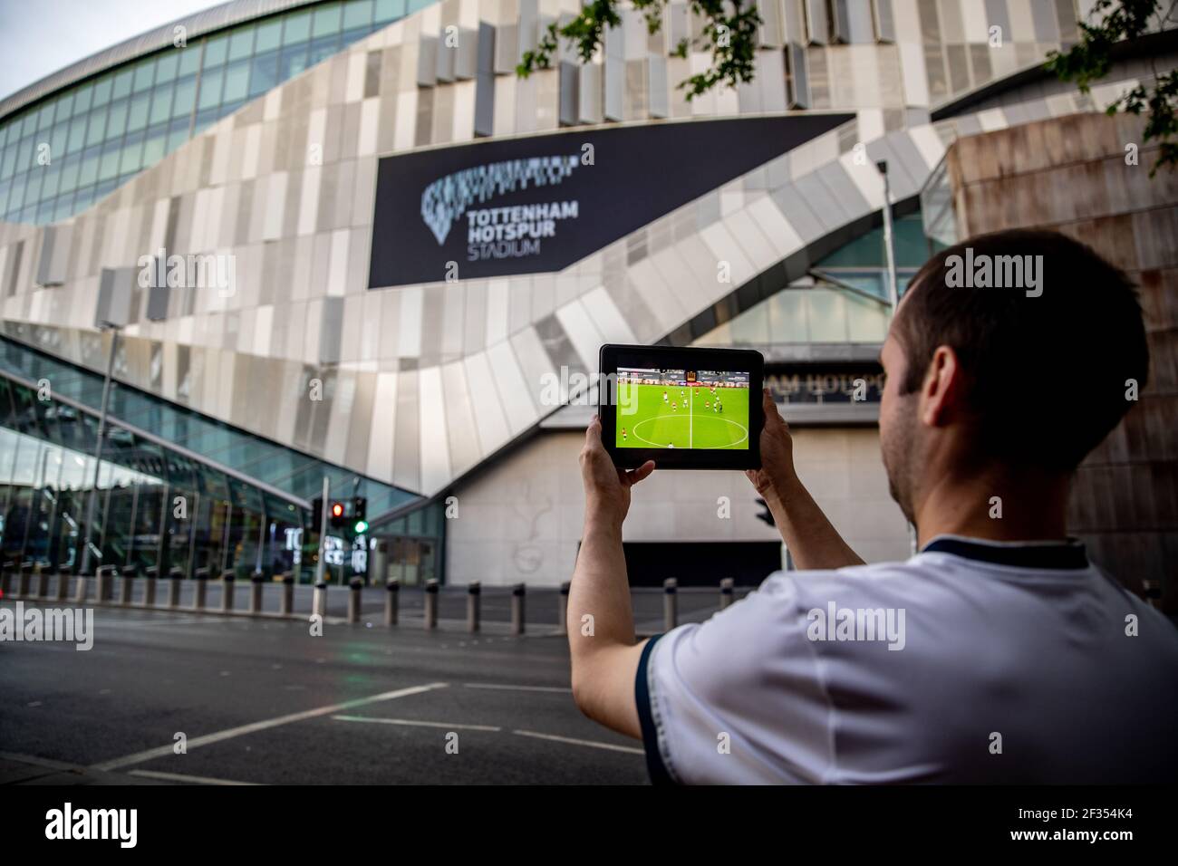 Tottenham Hotspur fan watching the game on the SKY Go app on the iPad outside the ground during the Premier League match back following the Coronaviru Stock Photo