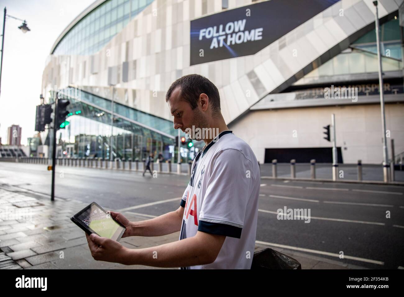 Tottenham Hotspur fan watching the game on the SKY Go app on the iPad outside the ground during the Premier League match back following the Coronaviru Stock Photo