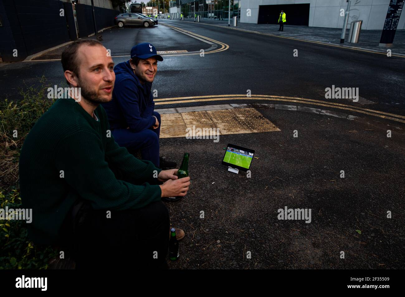 Two Tottenham Hotspur fans watching the game Sky GO app on the iPad outside the ground during the Premier League match back following the Coronavirus Stock Photo