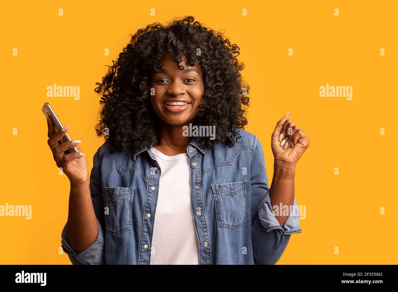Excited black woman with smartphone raising hands up Stock Photo