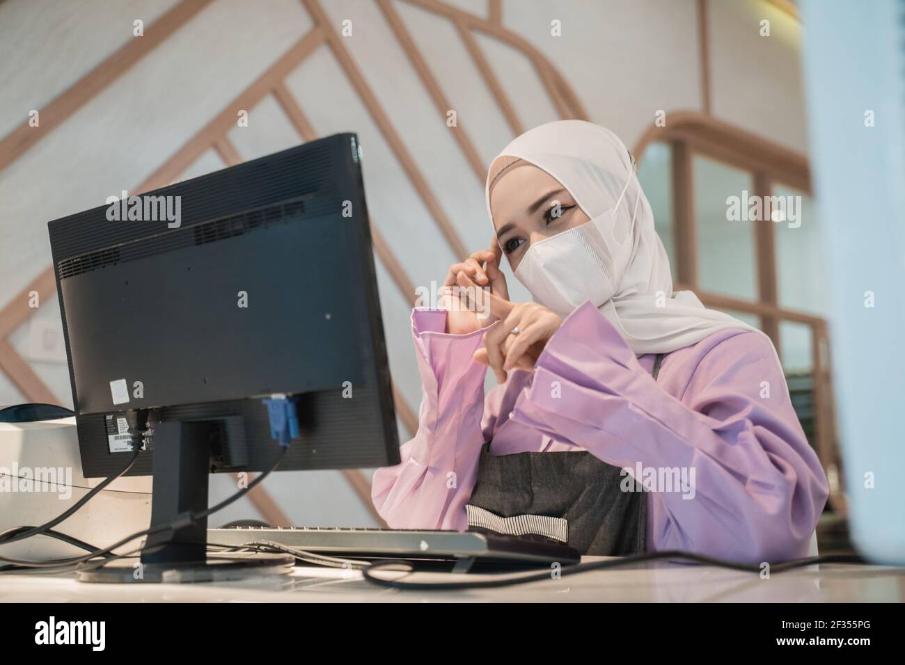 muslim asian woman working using pc while wearing medical face mask ...