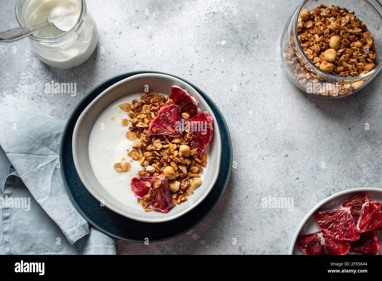 bowl with natural yogurt, granola and bloody orange on a gray concrete background. Clean eating. horizontal image, copy space, flat lay. Stock Photo