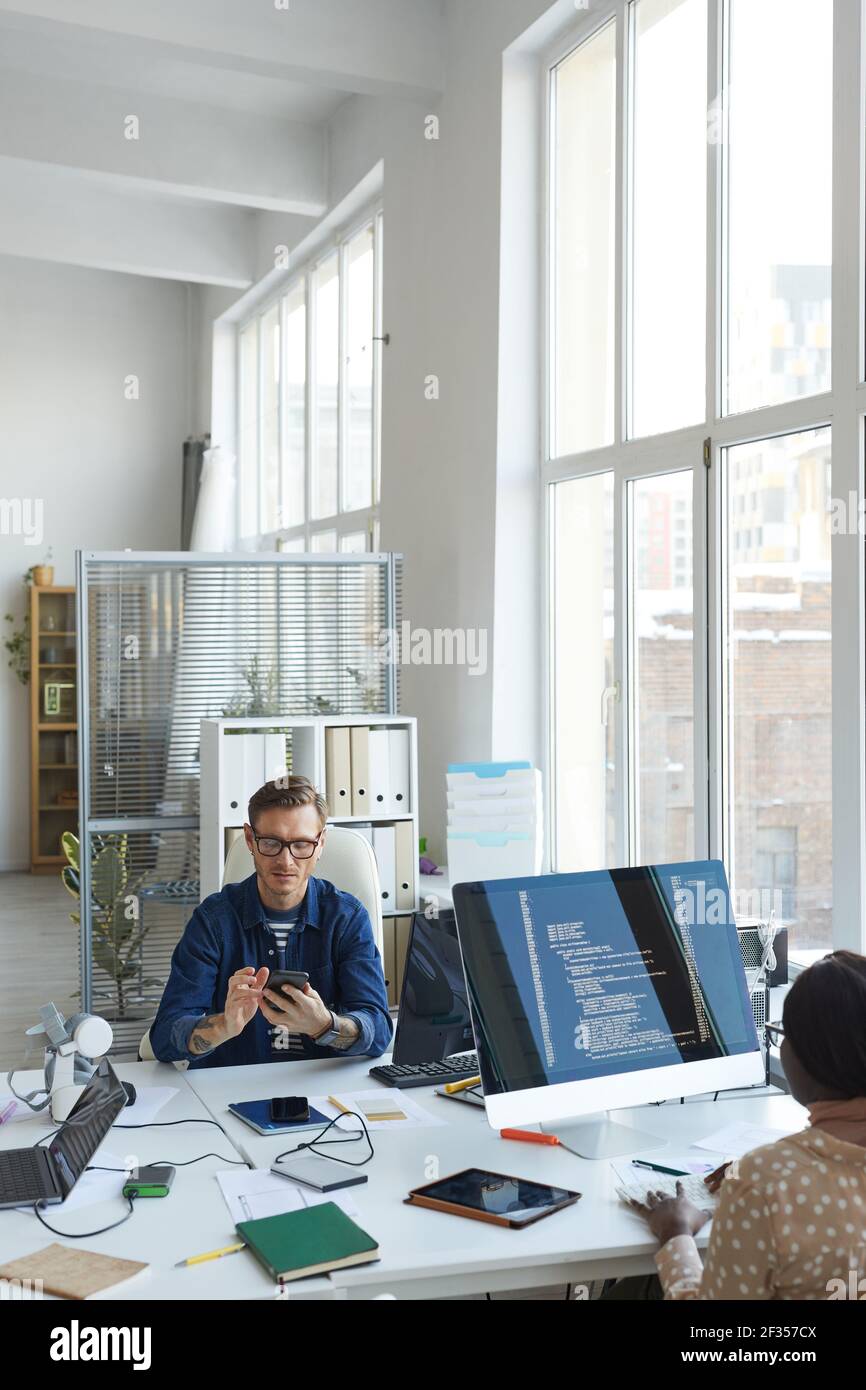 Vertical portrait of modern IT developers using computers for code programming while working on VR software in office, copy space Stock Photo