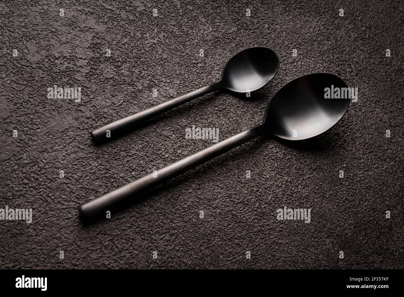 Spoons, teaspoons and regular ones, a couple. They're lying on a dark table. design for a