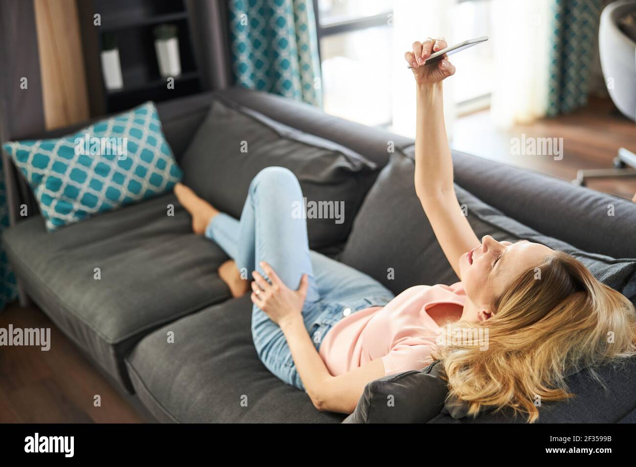 Charming woman lying on couch and making selfie at home Stock Photo - Alamy