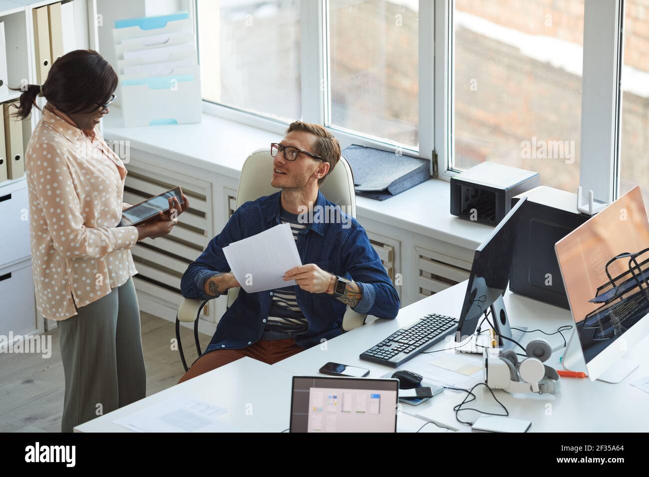 High angle portrait of two IT developers discussing projects while working on software and mobile applications office, copy space Stock Photo