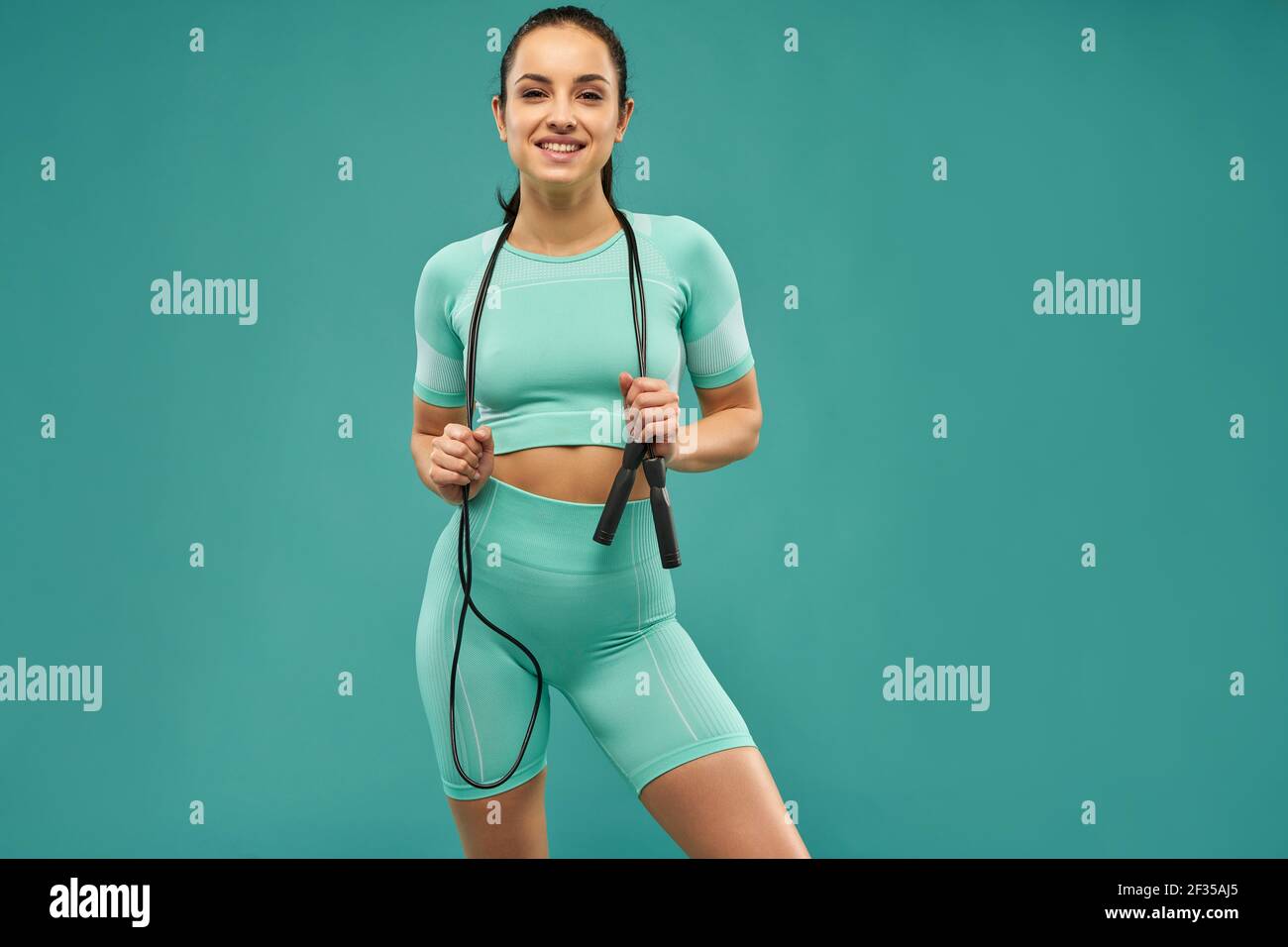 Sporty young woman with skipping rope posing in studio Stock Photo