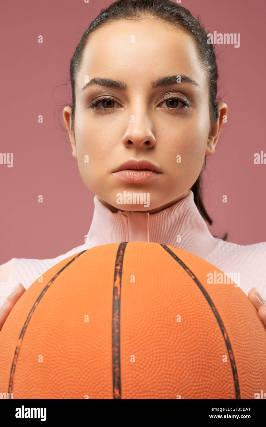 Attractive young woman with basketball ball posing in studio Stock Photo