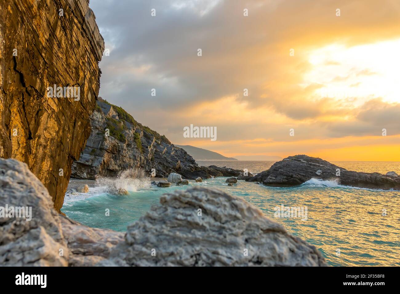Summer evening and a small beach on a rocky beach. Wave smashes on coastal rocks with lots of splashes Stock Photo