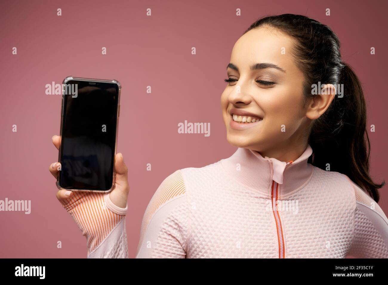 Cheerful young woman holding cellphone with black display Stock Photo