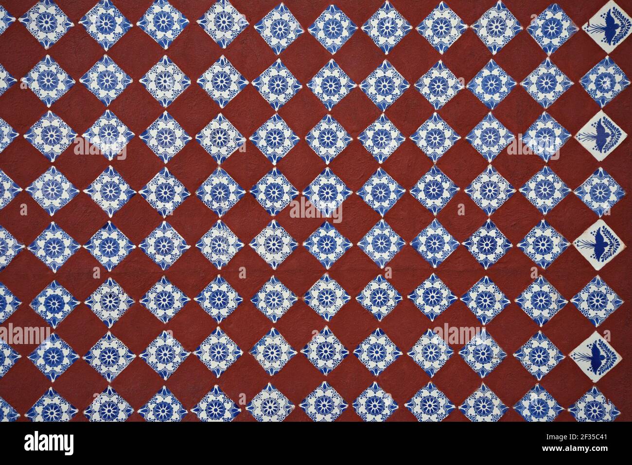 Terracotta and blue Talavera symmetrical tile pattern with white and ochre accents on the Baroque Santa María Tonantzintla wall in Cholula, Mexico. Stock Photo