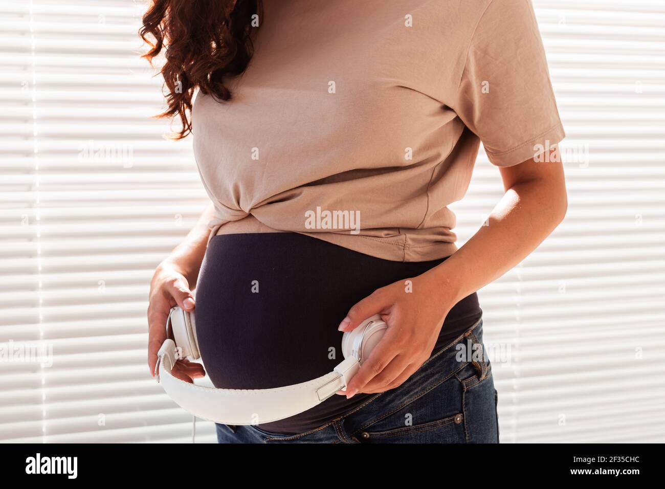 Hands of young pregnant woman put headphones with classical music on her pregnant  belly. Concept of intellectual intrauterine development of the child Stock  Photo - Alamy