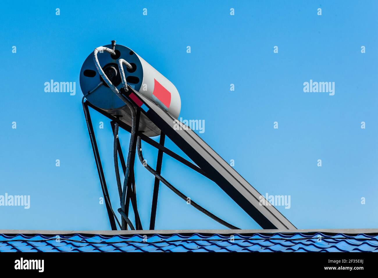 Solar water heater on the roof of a building against the background of the sky. Using solar energy to heat water. Stock Photo