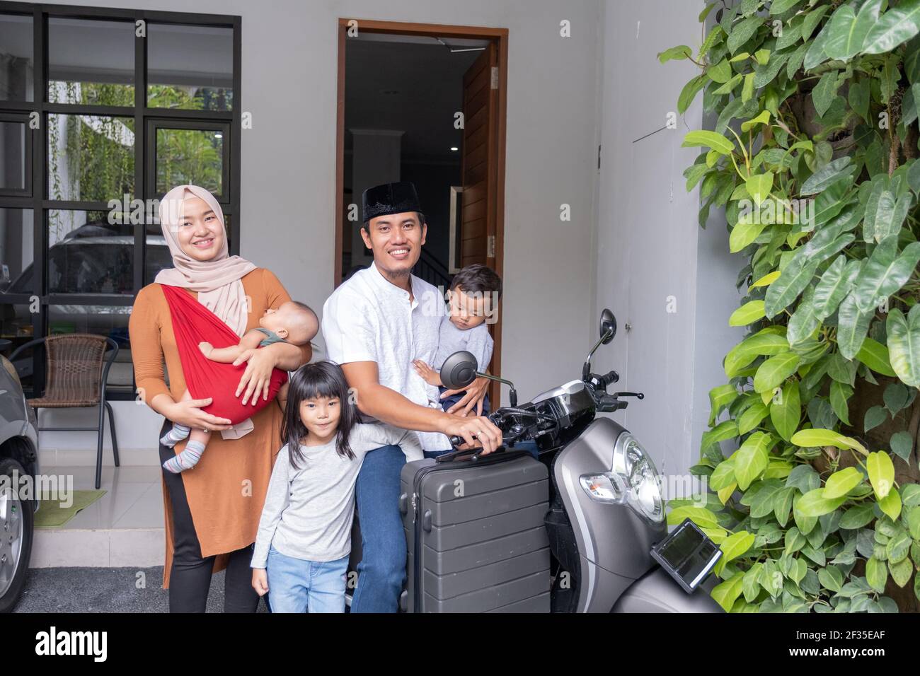 asian muslim family riding motorbike scooter together traveling with kid Stock Photo