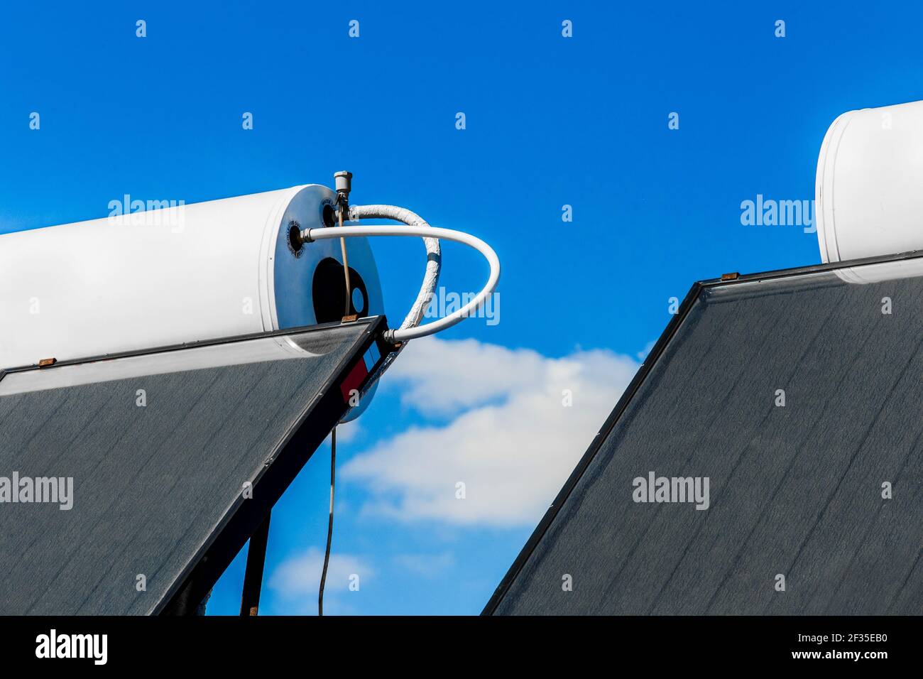 Solar water heater against the background of the blue sky. Using solar energy to heat water. Stock Photo