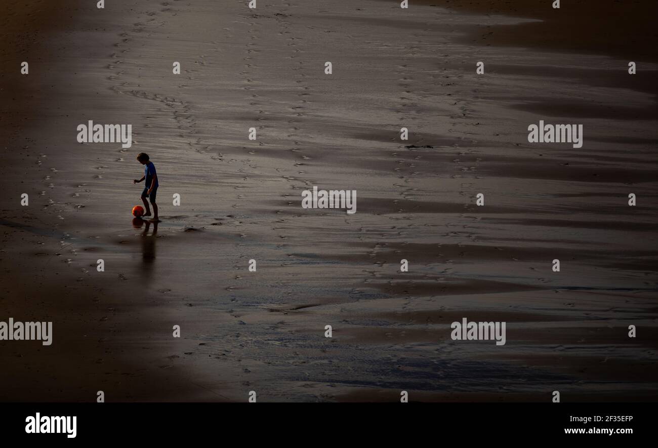A young boy playing with a football on Tynemouth Longsands at low tide