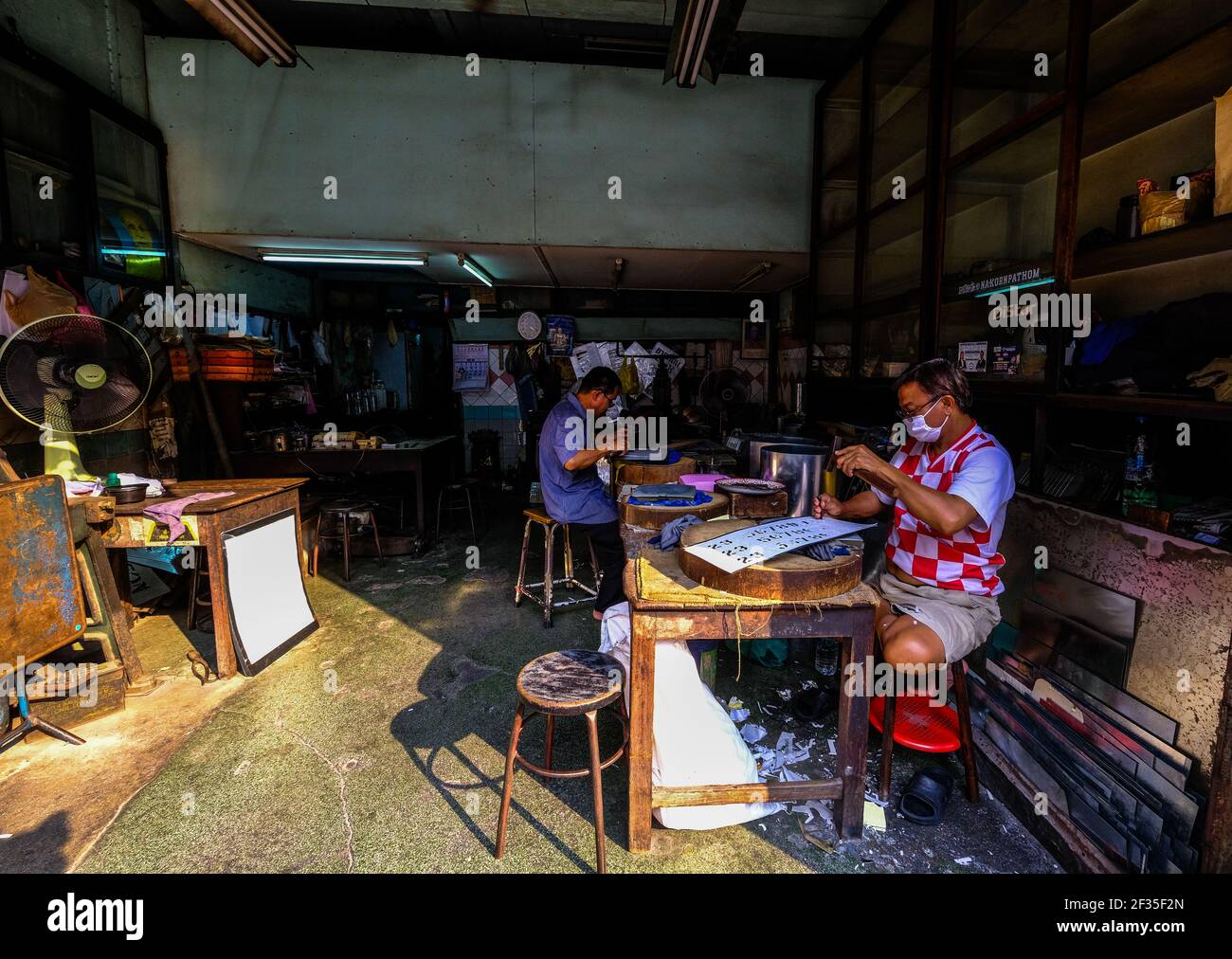 Two men work inside their workshop in the Chinatown area of Bangkok, Thailand Stock Photo