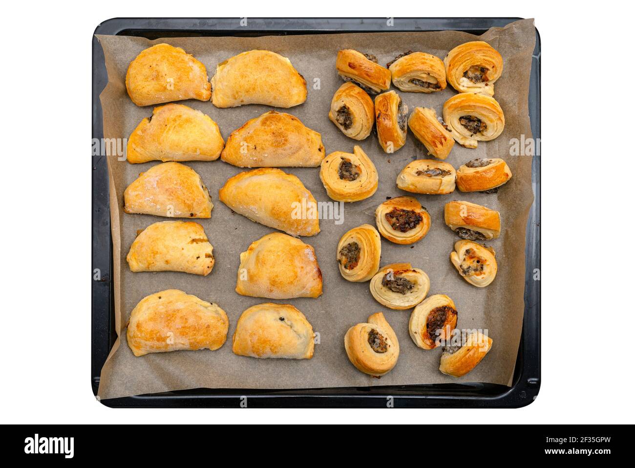 Frozen baked patties and dumplings in dough on a baking sheet on baking paper, isolated on a white background with a clipping path, top view. Stock Photo