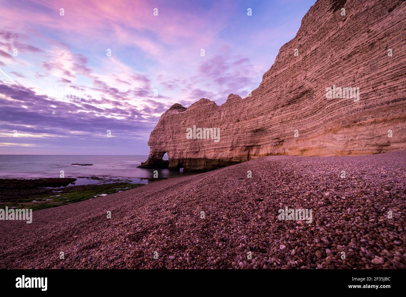 Tall and steep eroded chalk cliff at seacoast in twilight time. Pink