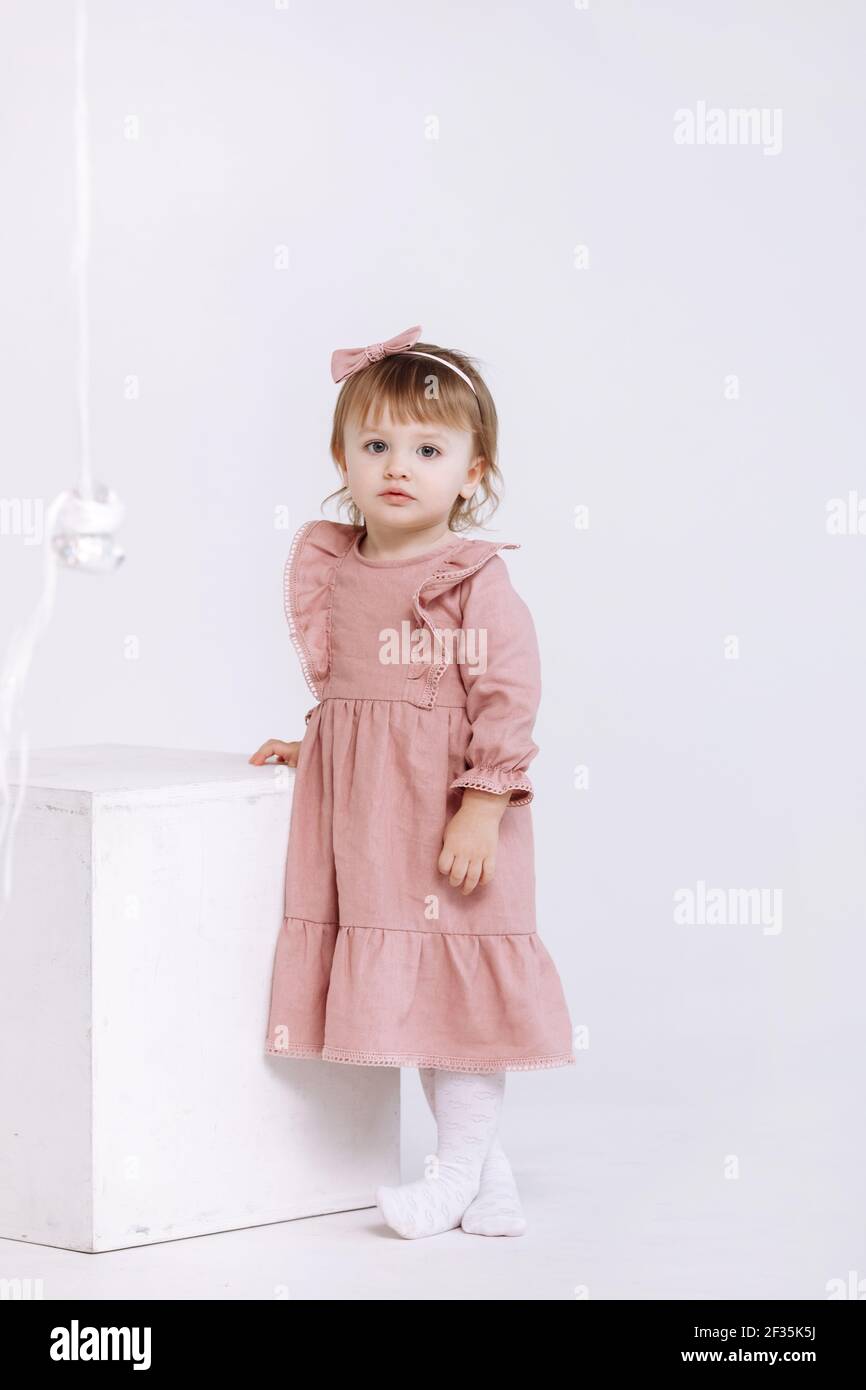 portrait of a little cute girl in a beautiful pink dress and bow on ...