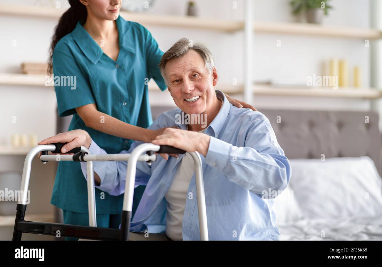 Disabled senior man receiving medical assistance from young caregiver