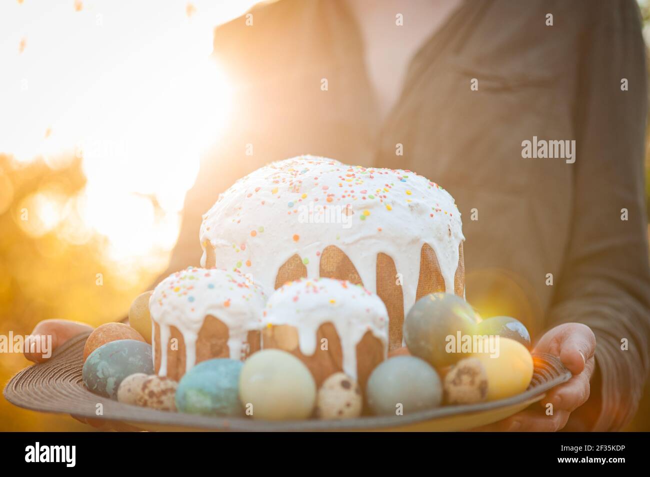 Girl holding a wooden plate with easter cake and eggs Stock Photo