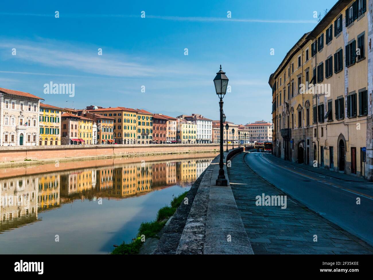 Historic lamp of street light of riverbank of Arno river, Pisa, Italy. Row of buildings reflected on water surface. Stock Photo