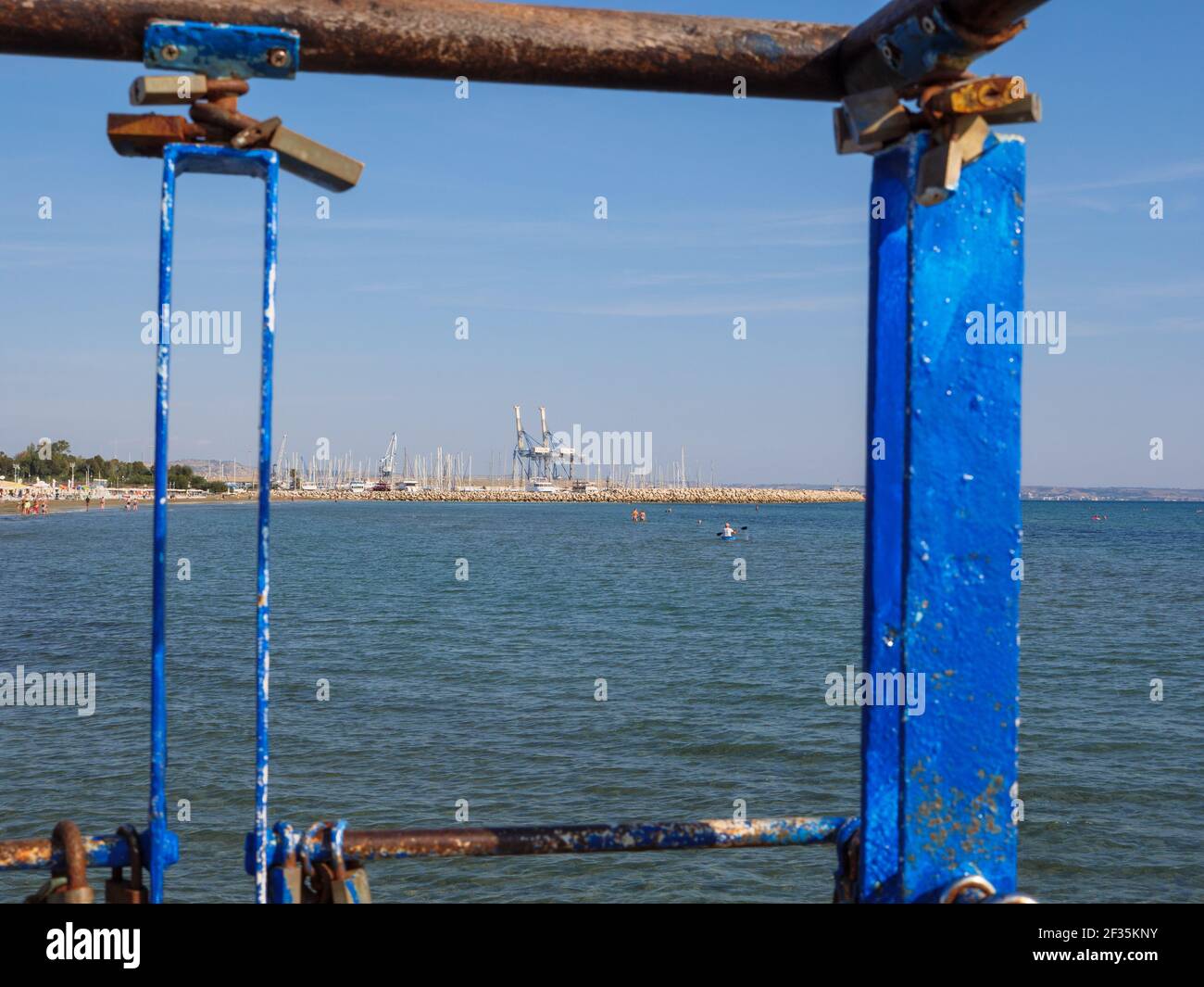 View from the pier over the man paddling in canoe and people swimming in the mediterranean sea in Larnaca, Cyprus. Stock Photo