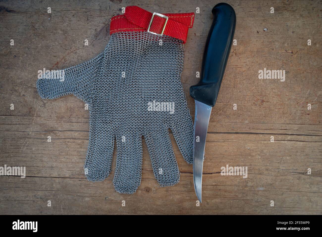 metal protective glove and kitchen knife on wooden table,for butchers or woodworking . Stock Photo