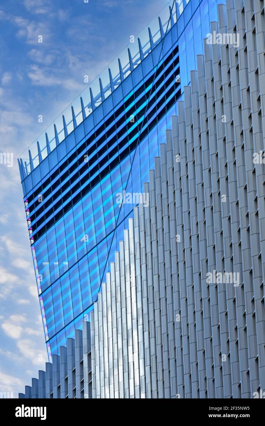 Abstract architecture & modern building materials in façade two office structures blue elevation by artificial lighting sunshine on grey cladding UK Stock Photo