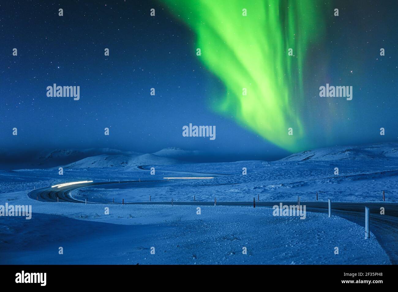 Northern Lights above snow covered icelandic winding road Stock Photo