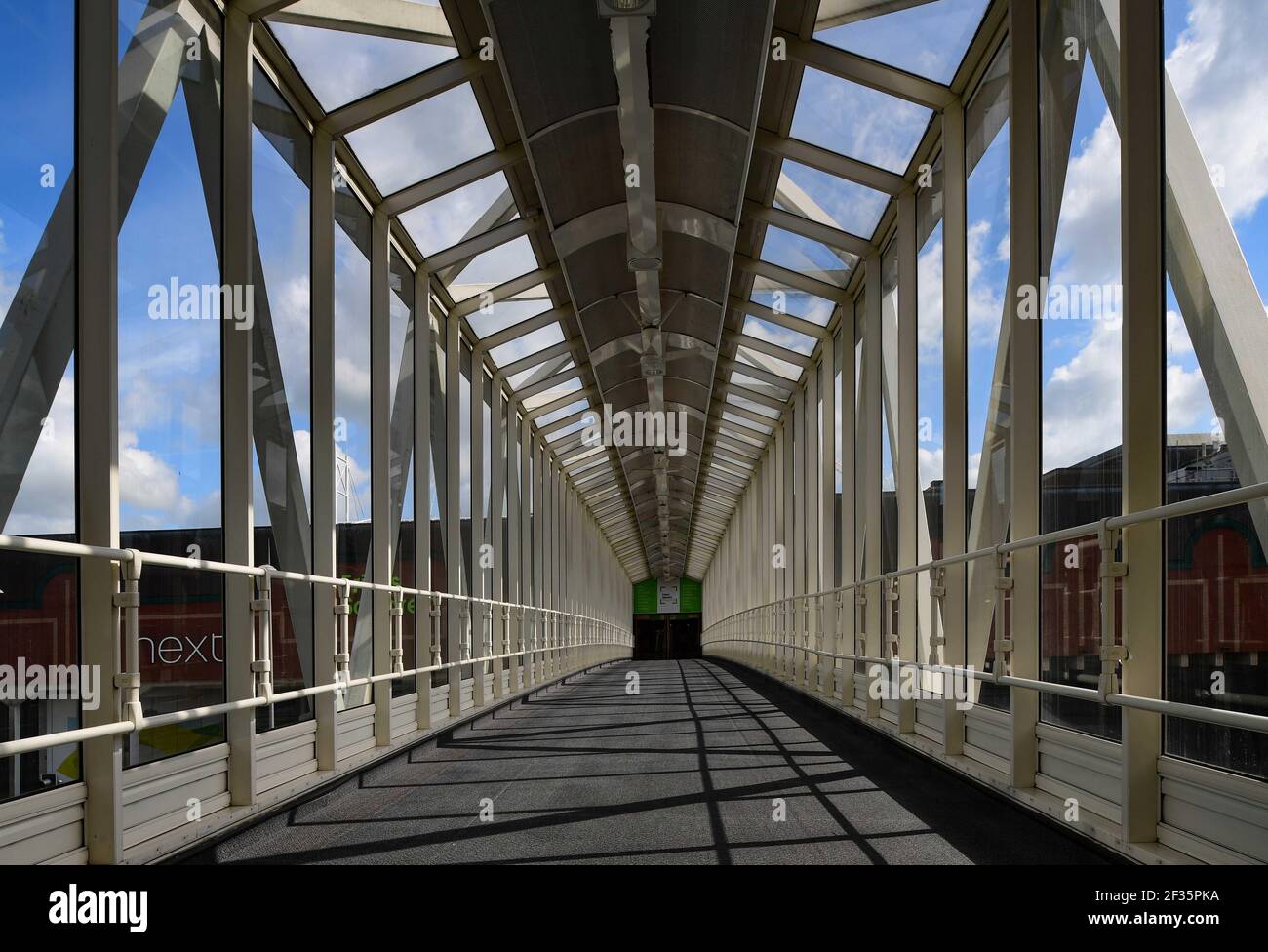 A view through a metal and glass bridge walkway Stock Photo