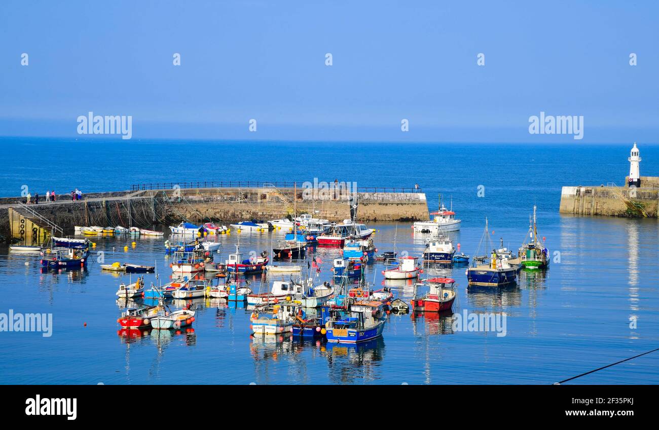 The view from Mevagissey, Cornwall out towards the harbour on a clear sunny day with blue skies with boats sheltering in the sea Stock Photo
