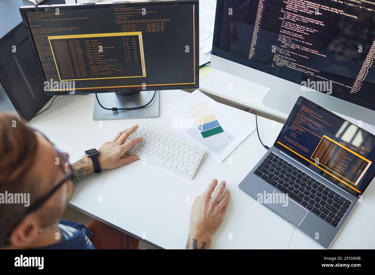 High angle view at male programmer writing code while using multiple computers in IT developers office , copy space Stock Photo