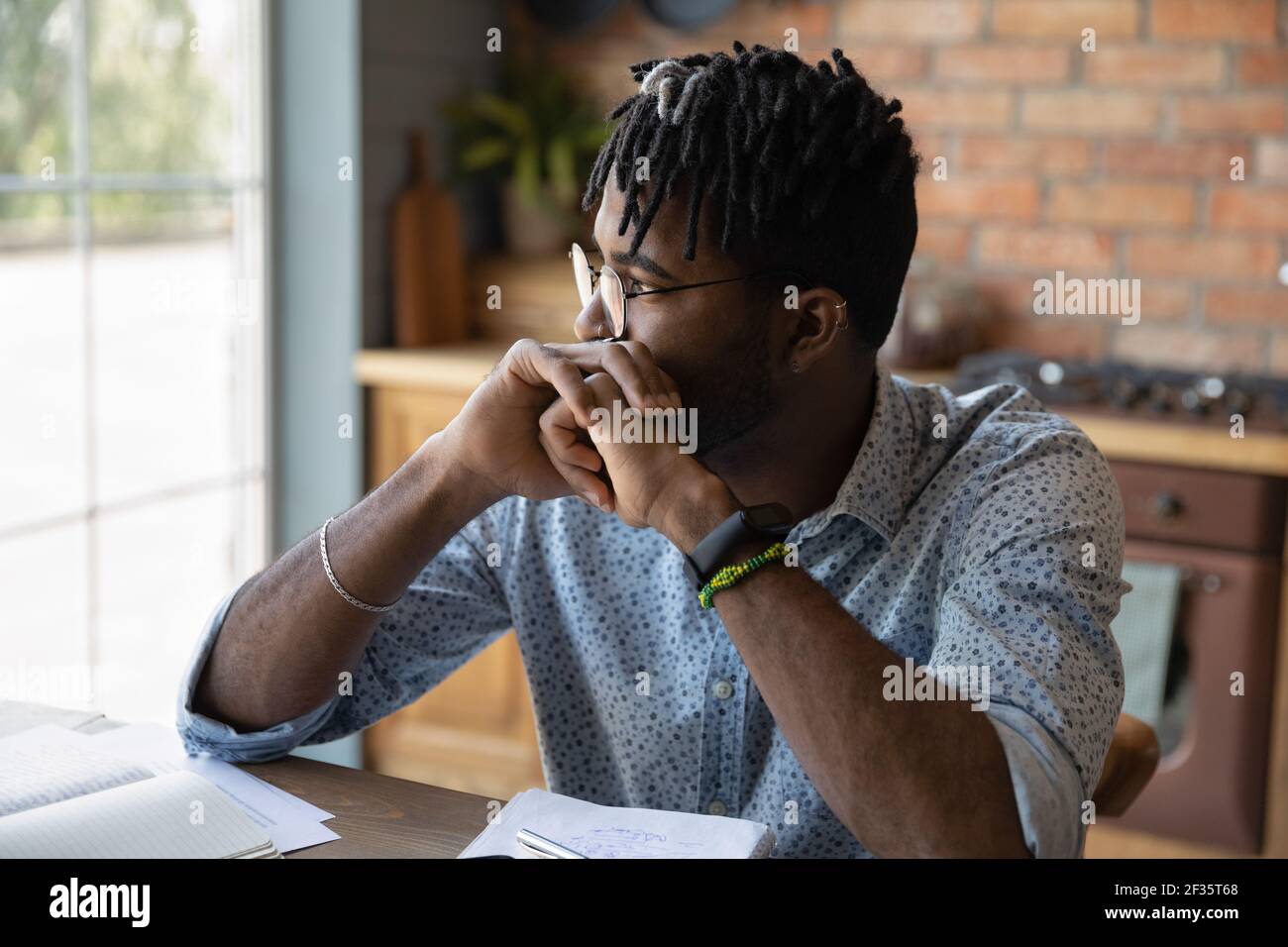 Pensive african male student sit at table reflect on task Stock Photo