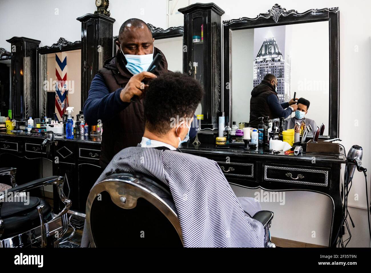 Porto, Portugal. 15th Mar, 2021. A hairdresser wearing a face mask cuts