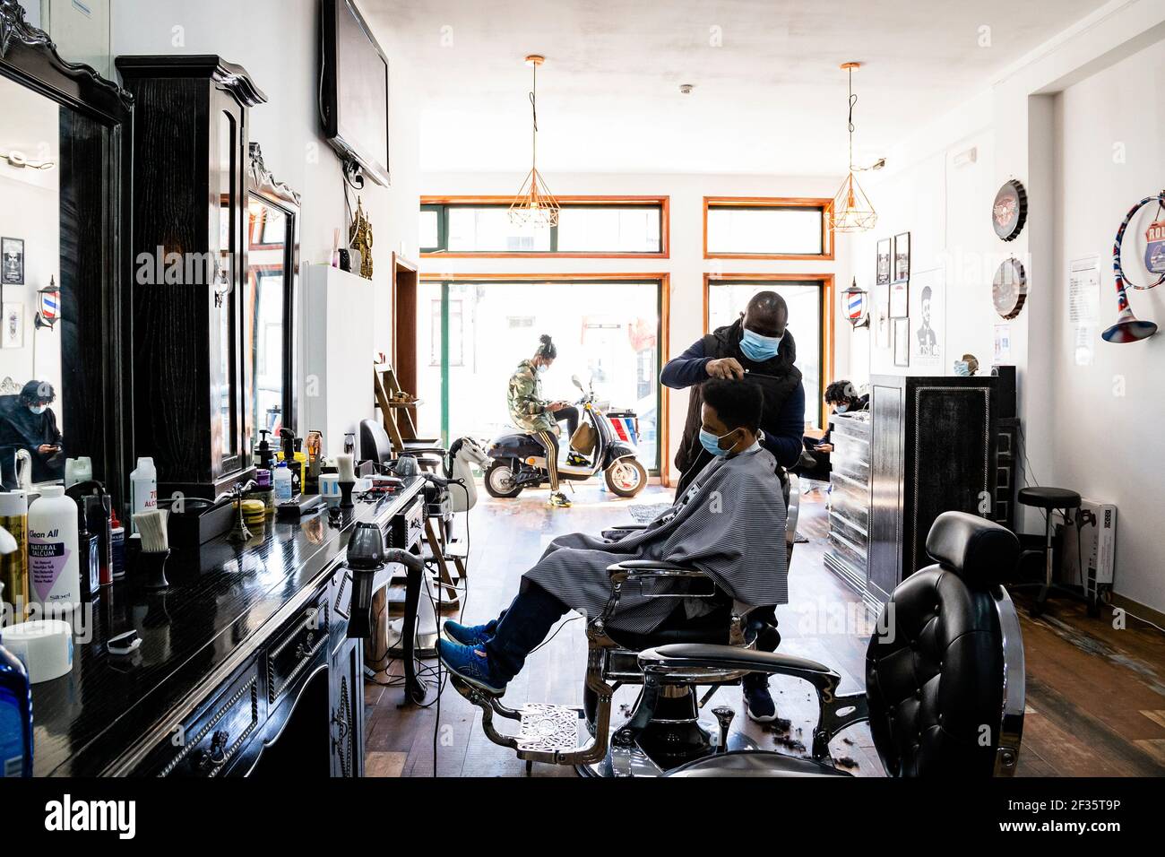 Porto, Portugal. 15th Mar, 2021. A hairdresser wearing a face mask cuts