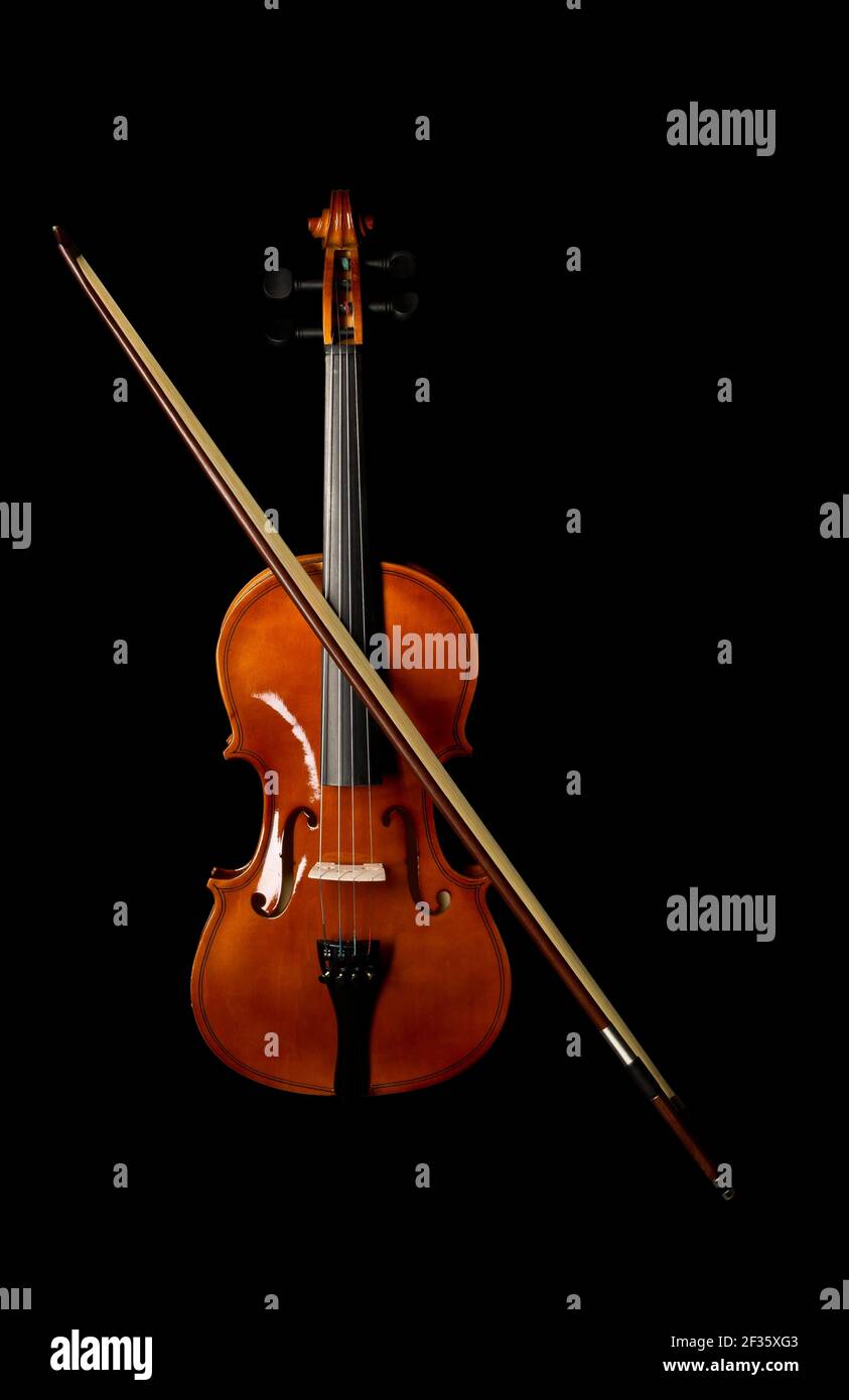 Brown wooden fiddle or violin, classic musical instrument, with bow isolated over black background, flat lay top view from above Stock Photo