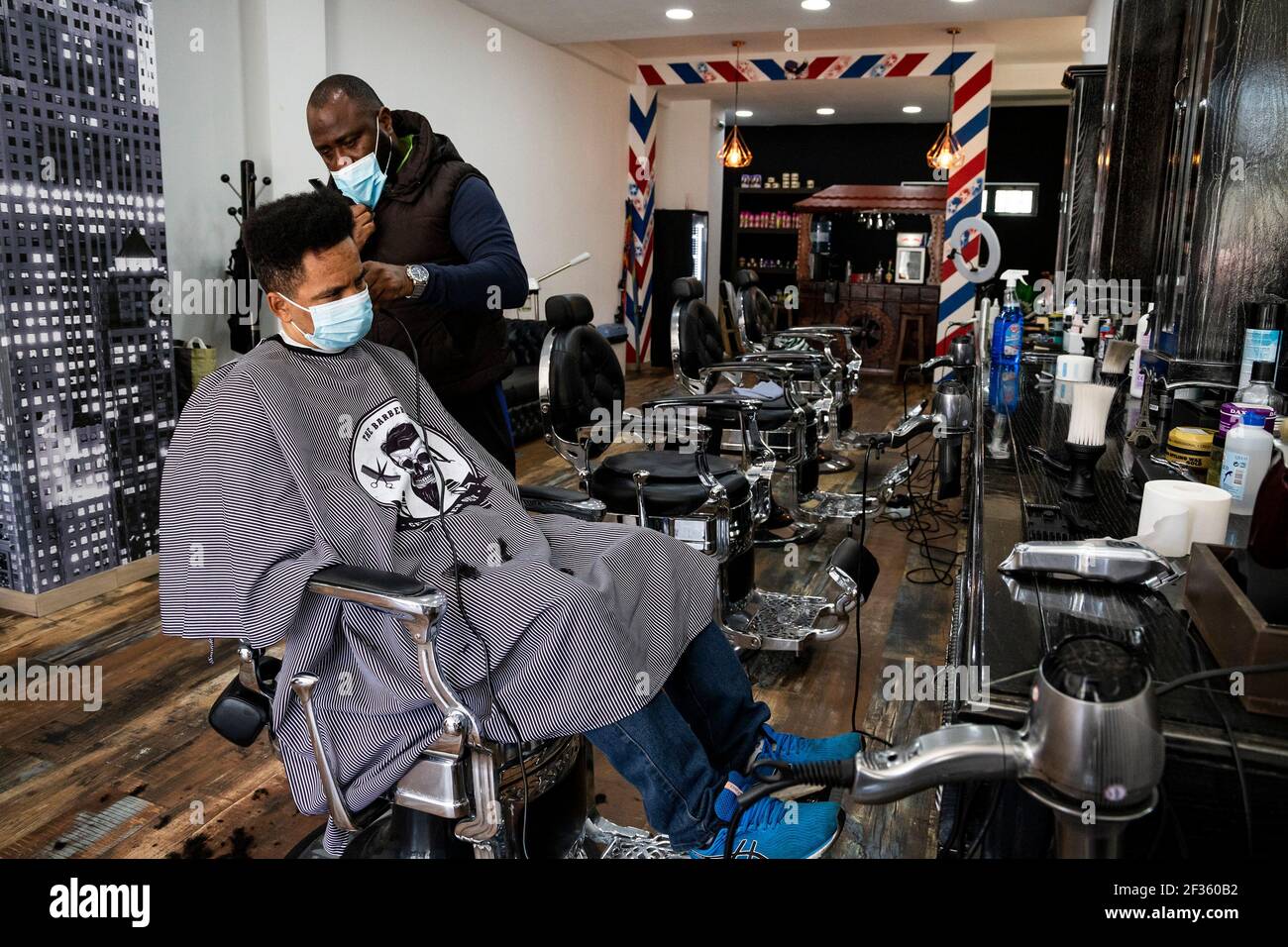 A hairdresser wearing a face mask cuts a costumers hair short at a